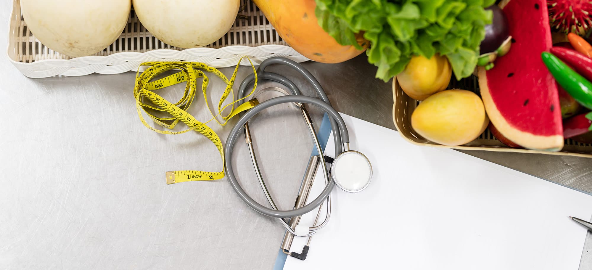 Tape measure, stethoscope and healthy food on a clinic desk